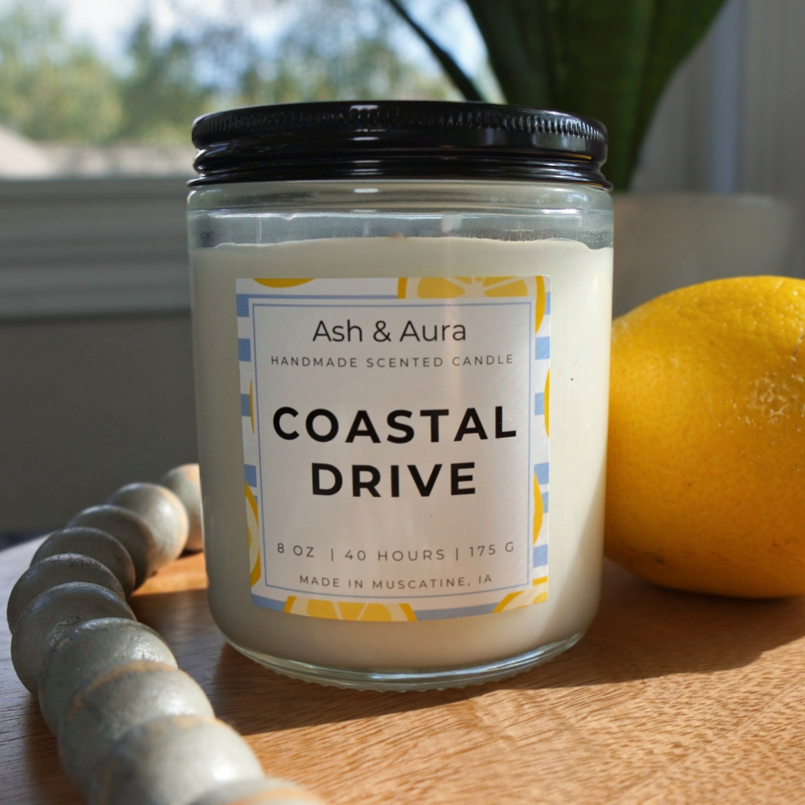 Coastal Drive soy blend candle in a [clear glass jar] with a white Ash & Aura label.